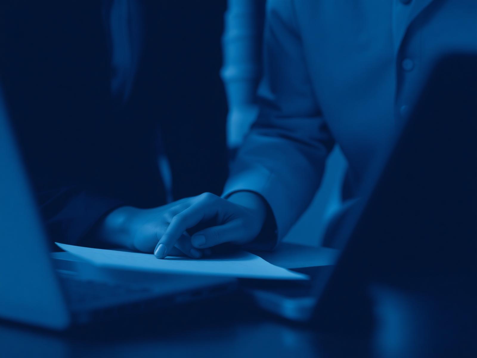 Two professionals reviewing documents together over a laptop